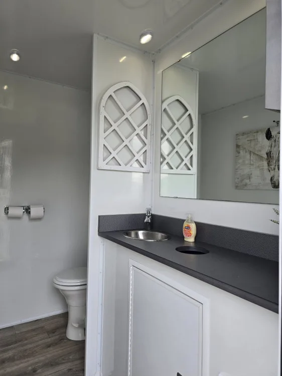 3-station ladies room with vanity, toilet and arched-window mirror