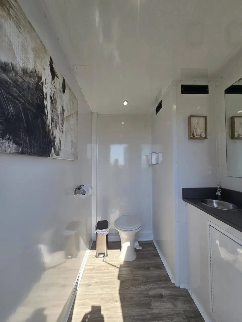 Sunlit private suite with horse artwork, vanity sink and wood-look floor